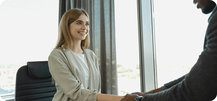 Young woman smiling and sitting by a window.